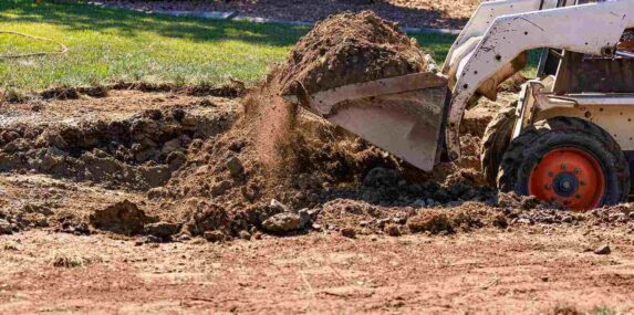 small bulldozer digging in yard for pool installation