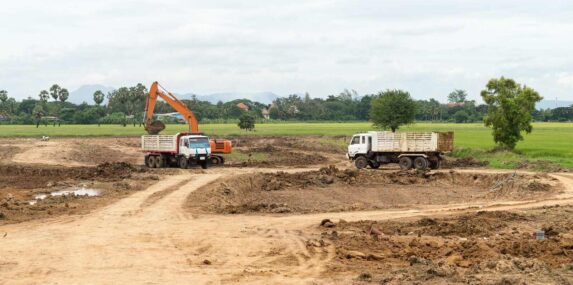 excavator machine moves with raised bucket on construction site