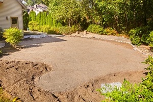 edges where the patio stones will go are marked loosely against the flowerbed and its potting soil