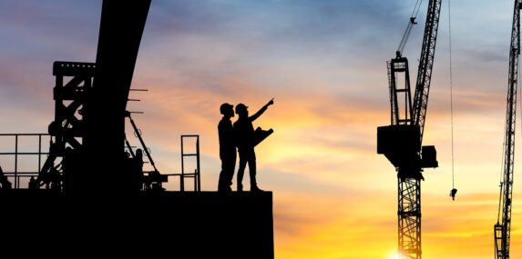 silhouette of engineer and worker checking project at heavy construction sand project site