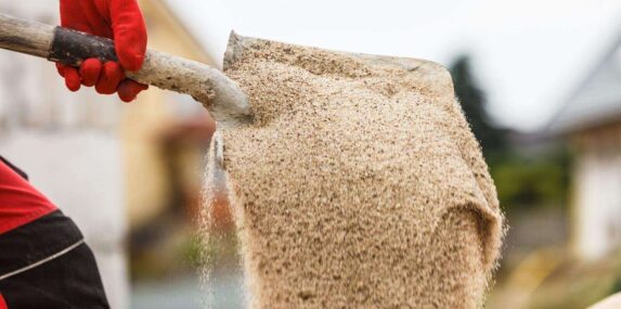 person shoveling concrete sand on construction site