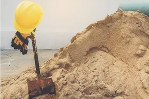 yellow helmets, gloves and shovel on the sand pile