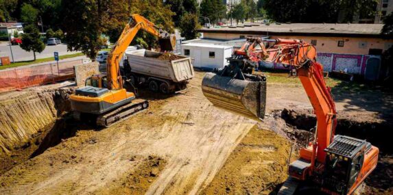 ariel view excavator is loading a truck with fill dirt to on building site in Punta Gorda, FL