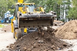 bulldozer is actively loading soil into a sizable pile on a construction site