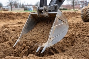 Excavator Bucket Digging into Pile of Dirt