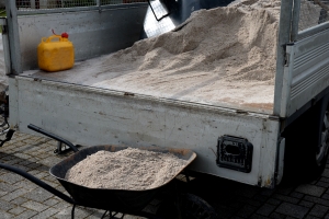 Unloading White Sand Using a Wheelbarrow from the Body of a Truck